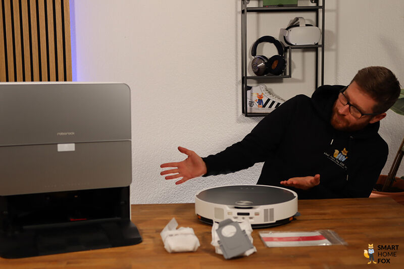 Ein Smart Home Fox Mitarbeiter zeigt mit den Händen auf den Roborock Saros 10 und die RockDock Station.